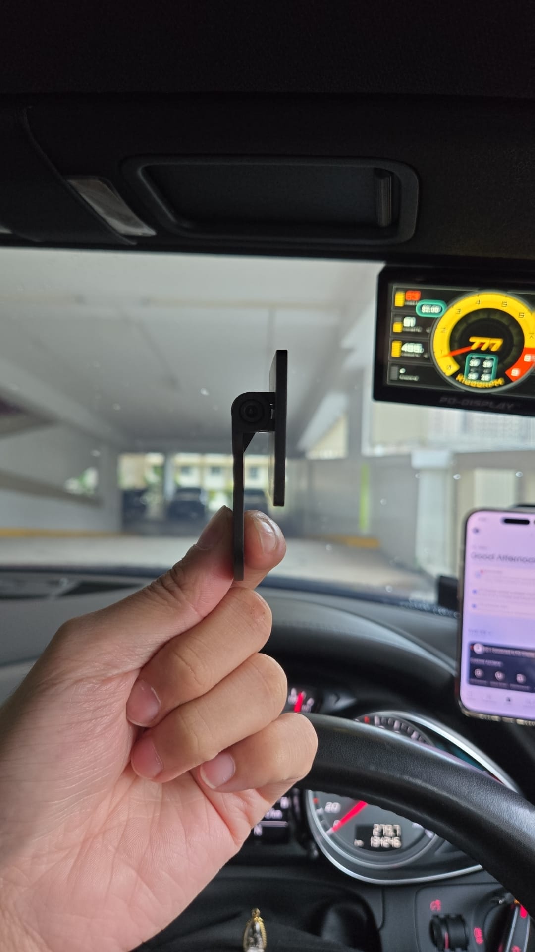 Side view of the black PD-Display mounting bracket held inside a car, showing its hinged arm.